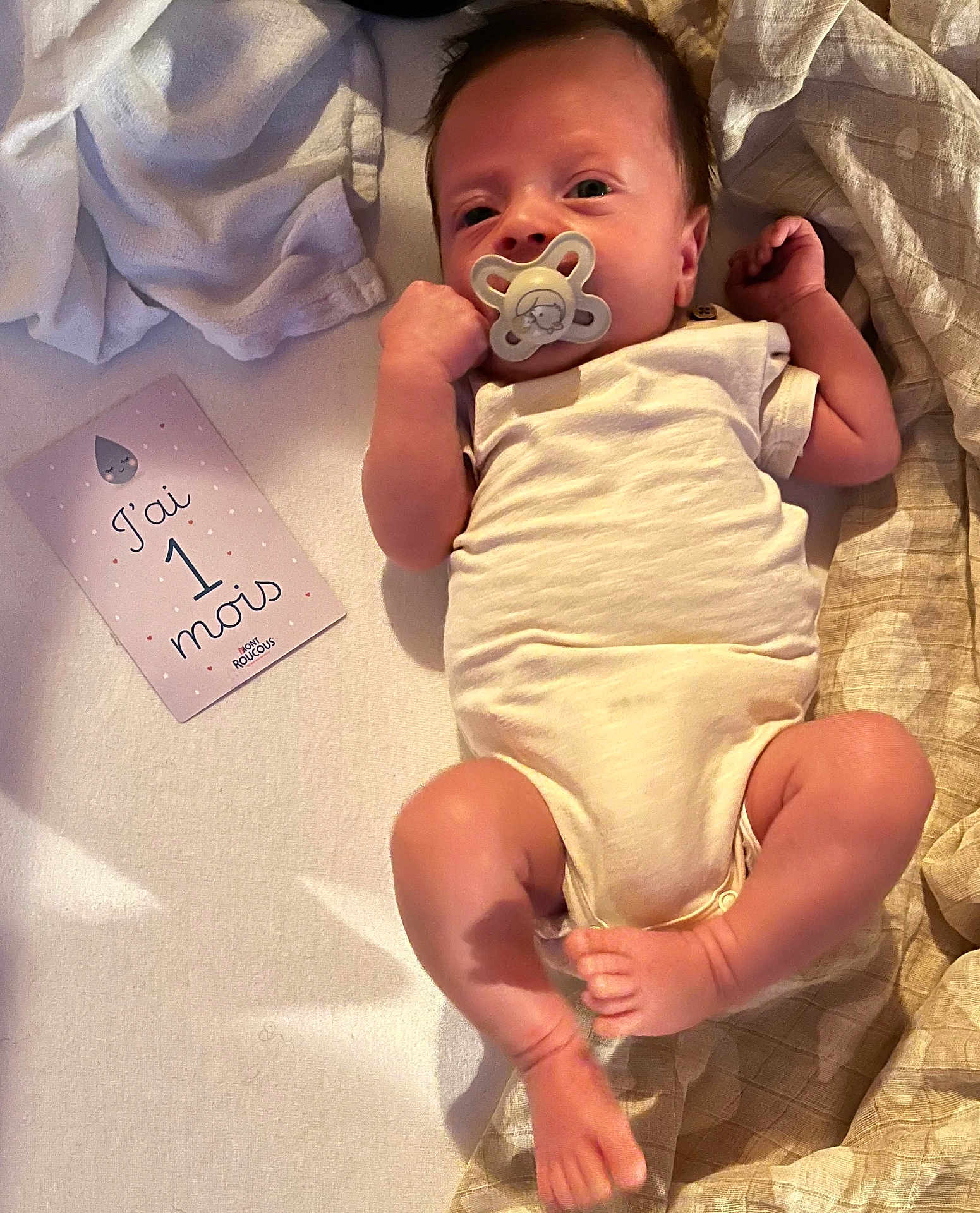 Liam a rejoint le concours — aidez-le/la à gagner de superbes lots ! baby, infant, pacifier, onesie, blanket, card, newborn, lying_down, soft_fabric, cute, small, child, skin, foot, hand, face, indoors, sleepwear, resting, one_month