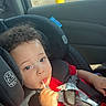 toddler, child, car_seat, red_shirt, lollipop, curly_hair, seatbelt, car_interior, window, daylight, parking_lot, blue_sky, sunlight, safety, young_child, portrait, cute, baby, seat, vehicle