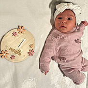 Amira joined the competition — help win amazing prizes! adorable, baby, bow, cozy, flower_decor, headband, infant, knitted_outfit, looking_up, lying_down, milestone_month, milestone_sign, newborn, pink_sweater, portrait_photo, soft_texture, tiny_hand, white_blanket, wide_eyes, wooden_prop