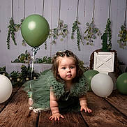 Joy joined the competition — help win amazing prizes! baby, child, green_balloon, white_balloon, green_dress, crawling, wooden_floor, birthday, first_birthday, decorations, greenery, crate, number_one, studio_photo, celebration, cute, portrait, indoor, person, floor