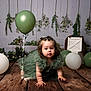baby, child, green_balloon, white_balloon, green_dress, crawling, wooden_floor, birthday, first_birthday, decorations, greenery, crate, number_one, studio_photo, celebration, cute, portrait, indoor, person, floor
