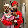 Keyunna joined the competition — help win amazing prizes! child, toddler, woman, mirror, selfie, bathroom, red_hoodie, braided_hair, headband, bow, pacifier, bib, sneakers, tiles, stall, phone, hand, pink_clothing, casual_wear, reflection
