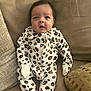 Leilani joined the competition — help win amazing prizes! baby, infant, onesie, leopard_print, couch, sofa, pillow, indoor, child, cute, face, expression, clothing, sitting, cozy, small, young, person, home, relaxed
