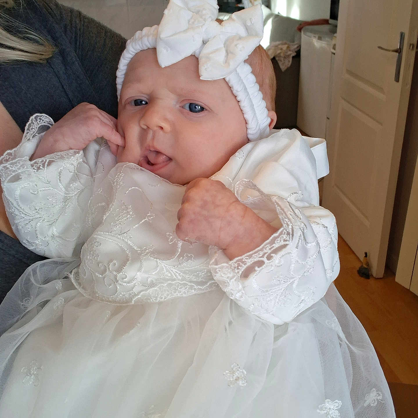 Emilia participe au concours pour gagner de l'argent avec cette photo : baby, bow, child, clothing, curious, cute, fabric, face, hand, headband, holding, home, indoor, infant, lace, newborn, person, portrait, soft_light, white_dress
