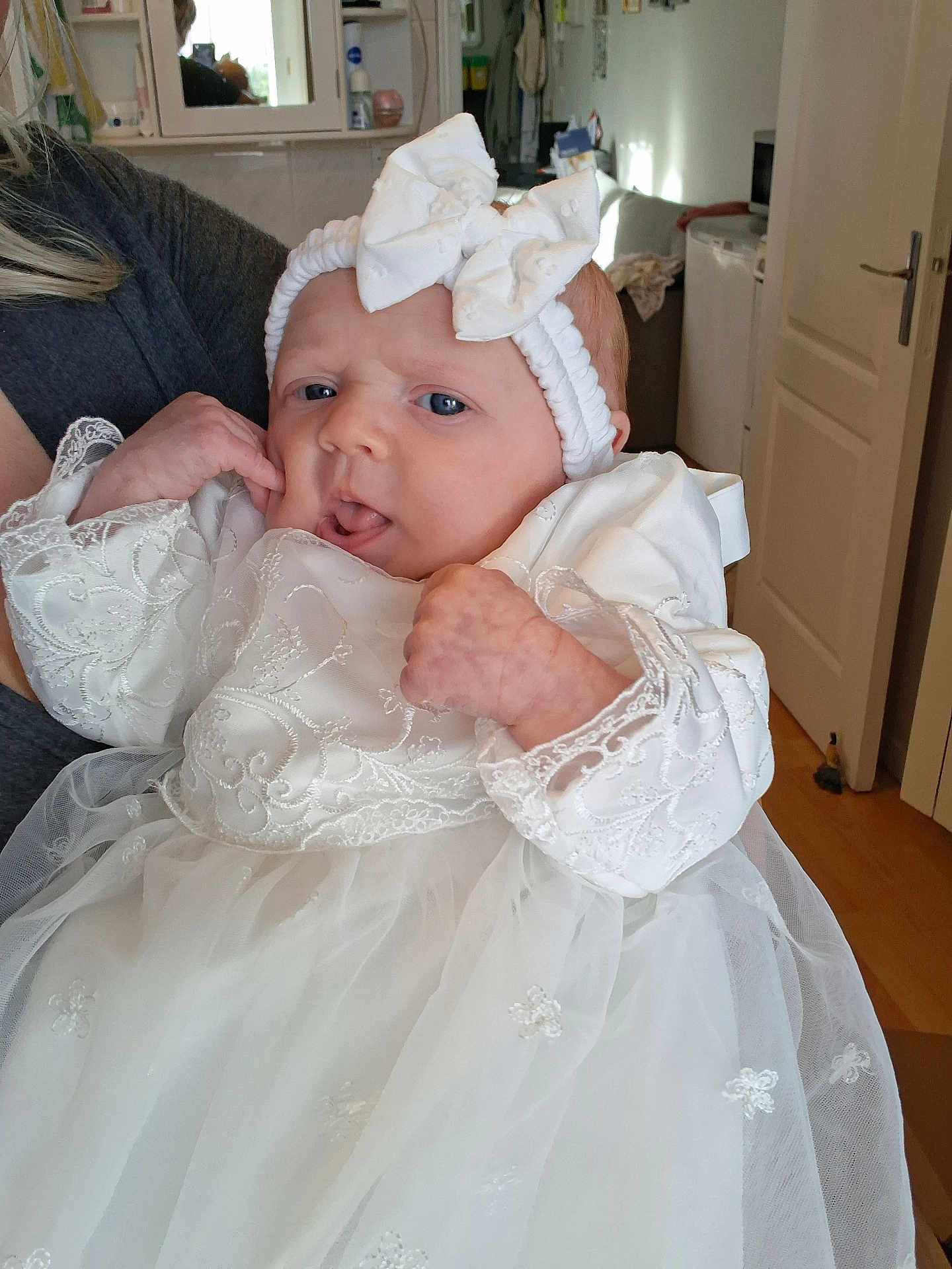 Emilia participe au concours pour gagner de l'argent avec cette photo : baby, infant, white_dress, headband, bow, hand, face, indoor, person, curious, lace, fabric, clothing, portrait, newborn, cute, child, holding, soft_light, home