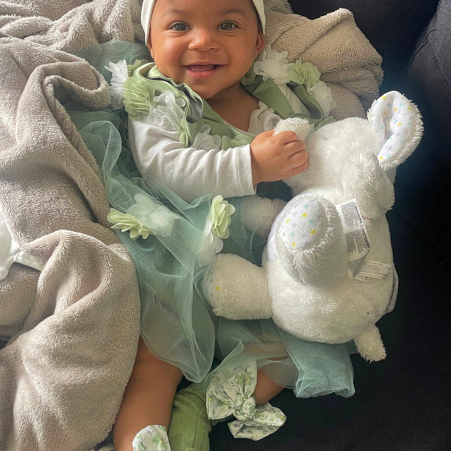 Tyannah a rejoint le concours — aidez-le/la à gagner de superbes lots ! baby, blanket, bunny, child, couch, cozy, cute, fabric, green_dress, happy, headband, indoor, person, plush_toy, portrait, seated, smiling, socks, soft_toy, toddler