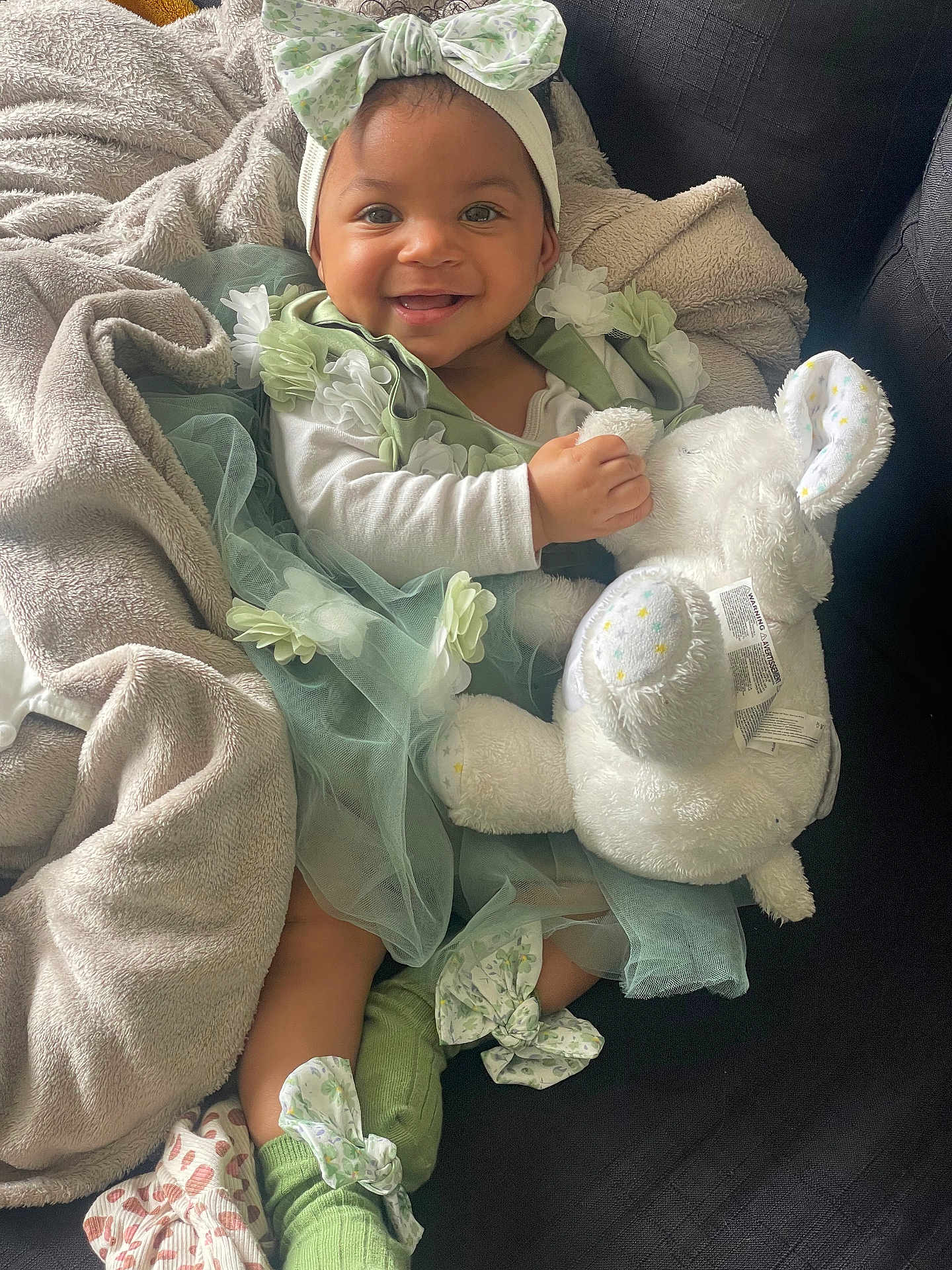 Tyannah a rejoint le concours — aidez-le/la à gagner de superbes lots ! baby, blanket, bunny, child, couch, cozy, cute, fabric, green_dress, happy, headband, indoor, person, plush_toy, portrait, seated, smiling, socks, soft_toy, toddler