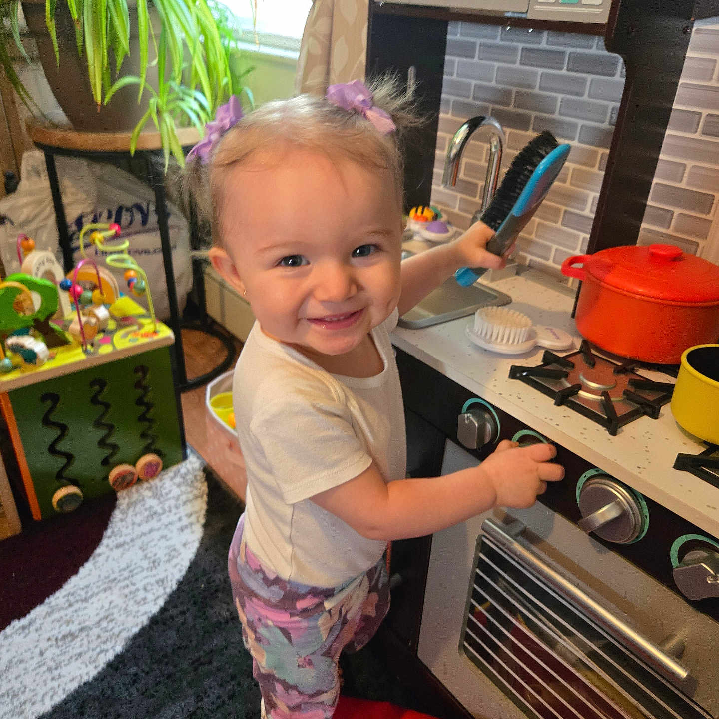 Kailyana joined the competition — help win amazing prizes! barefoot, carpet, child, colorful, curtain, cushion, furniture, hair_bows, happy, indoor, living_room, plant, play, pretend_play, smile, toddler, toy_brush, toy_kitchen, toy_pot, window