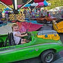 Kailyana joined the competition — help win amazing prizes! child, toddler, bumper_car, carnival, amusement_park, ride, green_car, smile, happy, outdoor, daytime, people, seatbelt, steering_wheel, fun, play, vehicle, colorful, background, family