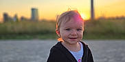 Kailyana joined the competition — help win amazing prizes! child, toddler, sunset, outdoor, smiling, jacket, face, person, nature, cityscape, sunlight, sky, grass, evening, portrait, young_child, casual_clothing, happy, warm_light, standing