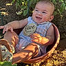 baby, infant, child, flower_pot, outdoor, garden, soil, plants, greenery, sunlight, shadow, smiling, holding, sign, wooden_sign, sitting, cute, summer, clothing, footwear