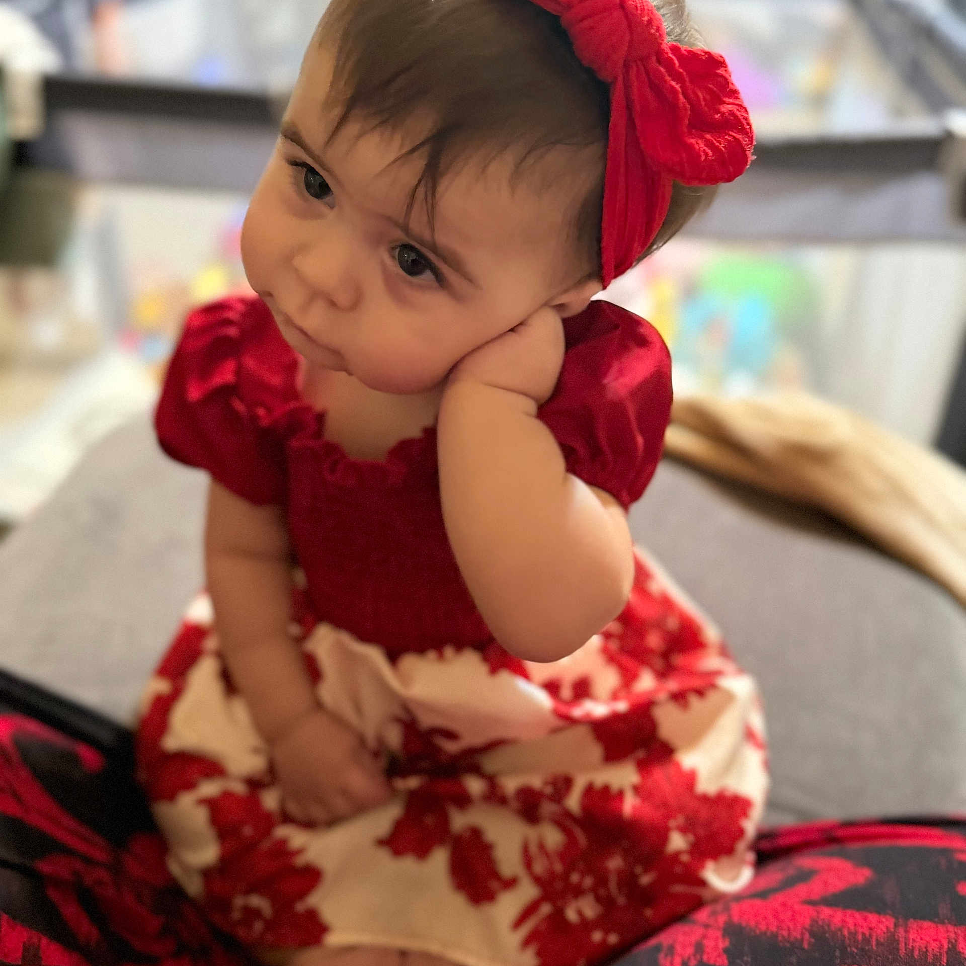Violet is registered to the contest to win money with this photo: baby, child, girl, red_headband, red_dress, floral_pattern, sitting, portrait, indoor, thoughtful, cute, face, hand, soft_focus, person, infant, clothing, young_child, expression, headwear