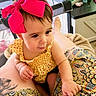 baby, child, pink_bow, yellow_dress, indoor, playpen, person, lap, curious, patterned_skirt, tattoo, skin, hand, foot, face, hair, closeup, candid, infant, home