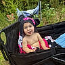 baby, black, child, cloth, cute, drool, face, greenery, happy, infant, nature, outdoor, person, pink, playful, polka_dot, sitting, stroller, summer, towel