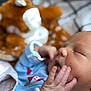 baby, newborn, sleeping, close_up, infant, hand, face, soft_toy, plush, blue_clothing, peaceful, resting, skin, cute, child, portrait, indoors, blanket, fingers, young