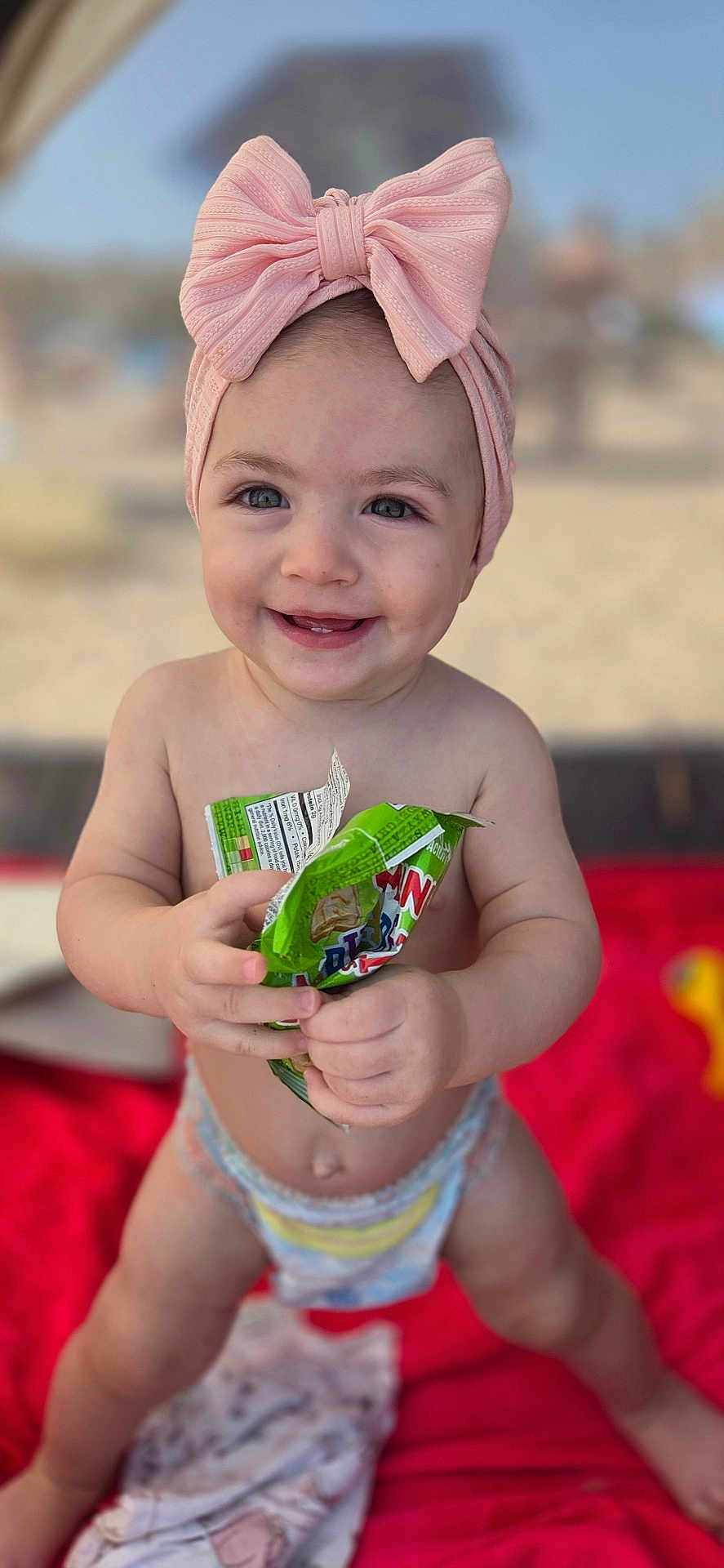 Tinatin joined the competition — help win amazing prizes! baby, child, diaper, pink_bow, headband, smiling, happy, snack_bag, outdoor, beach, red_blanket, infant, cute, portrait, bare_chest, playful, young_child, person, sunny, fun