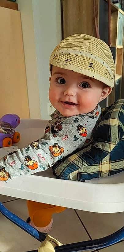 Lyra a rejoint le concours — aidez-le/la à gagner de superbes lots ! baby, baby_products, baby_toddler_clothing, cap, cheek, child, fashion_accessory, fun, happy, hat, headgear, headwear, pattern, person, plaid, room, sitting, sleeve, smile, t_shirt