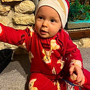 Lino participe au concours pour gagner de l'argent avec cette photo : baby, child, pajamas, red_clothing, hat, santa_hat, teddy_bear_pattern, carpet, stone_wall, aquarium, indoor, cute, smiling, person, holiday, festive, winter_clothing, sitting, reaching, cozy