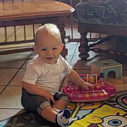 Lino participe au concours pour gagner de l'argent avec cette photo : toddler, child, toy, keyboard, spongebob, rug, smile, indoor, home, furniture, table, chair, socks, shorts, white_shirt, play, floor, baby, cute, happy