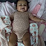 Serenity is registered to the contest to win money with this photo: baby, infant, child, smiling, lying_down, portrait, face, onesie, clothing, blanket, pink_blanket, bed, bedroom, indoor, cozy, patterned_fabric, pajamas, arms, legs, photography