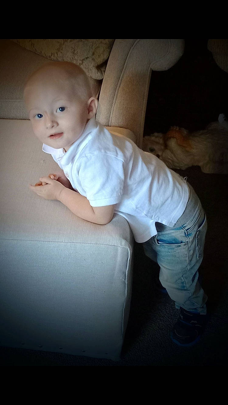 Axl is registered to the contest to win money with this photo: baby, baby_toddler_clothing, child, comfort, couch, darkness, flash_photography, flooring, fun, happy, human_leg, person, portrait_photography, room, sitting, toddler