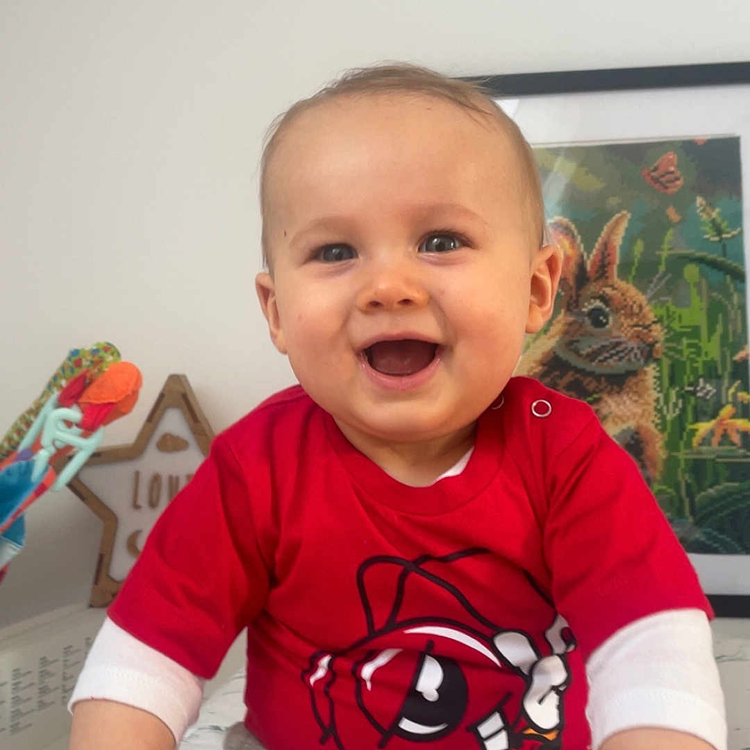 Louis a rejoint le concours — aidez-le/la à gagner de superbes lots ! artwork, baby, baby_girl_or_boy, cartoon_design, child, clothing, cute, face, frame, hand, happy, home, indoor, person, portrait, red_shirt, sitting, smiling, toy, young_child