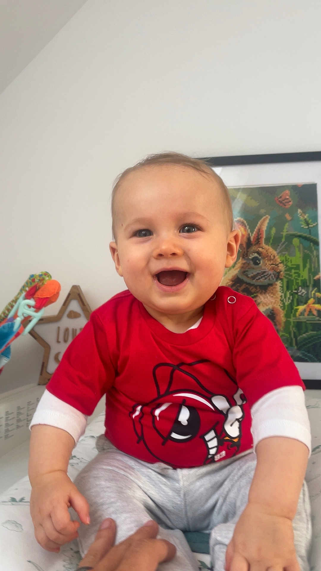 Louis a rejoint le concours — aidez-le/la à gagner de superbes lots ! baby, child, smiling, red_shirt, cartoon_design, sitting, indoor, toy, hand, face, person, happy, portrait, cute, young_child, clothing, artwork, frame, home, baby_girl_or_boy