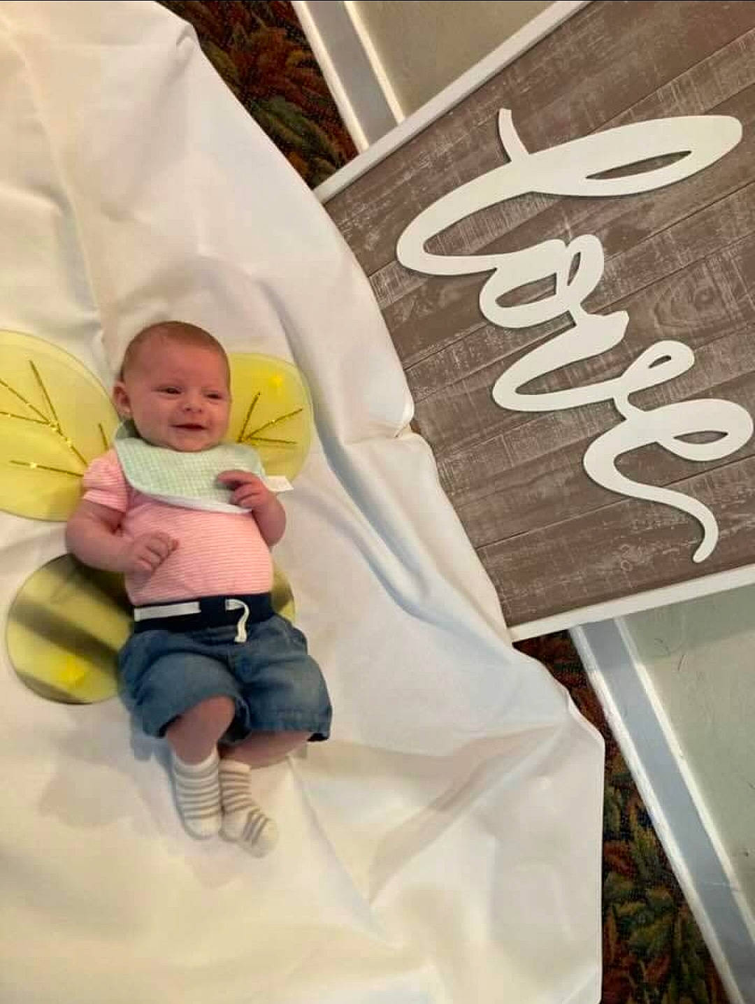 Elara is registered to the contest to win money with this photo: baby, baby_products, baby_safety, baby_toddler_clothing, child, comfort, font, fun, happy, joy, leisure, linens, person, room, sitting, sleeve, t_shirt, toddler