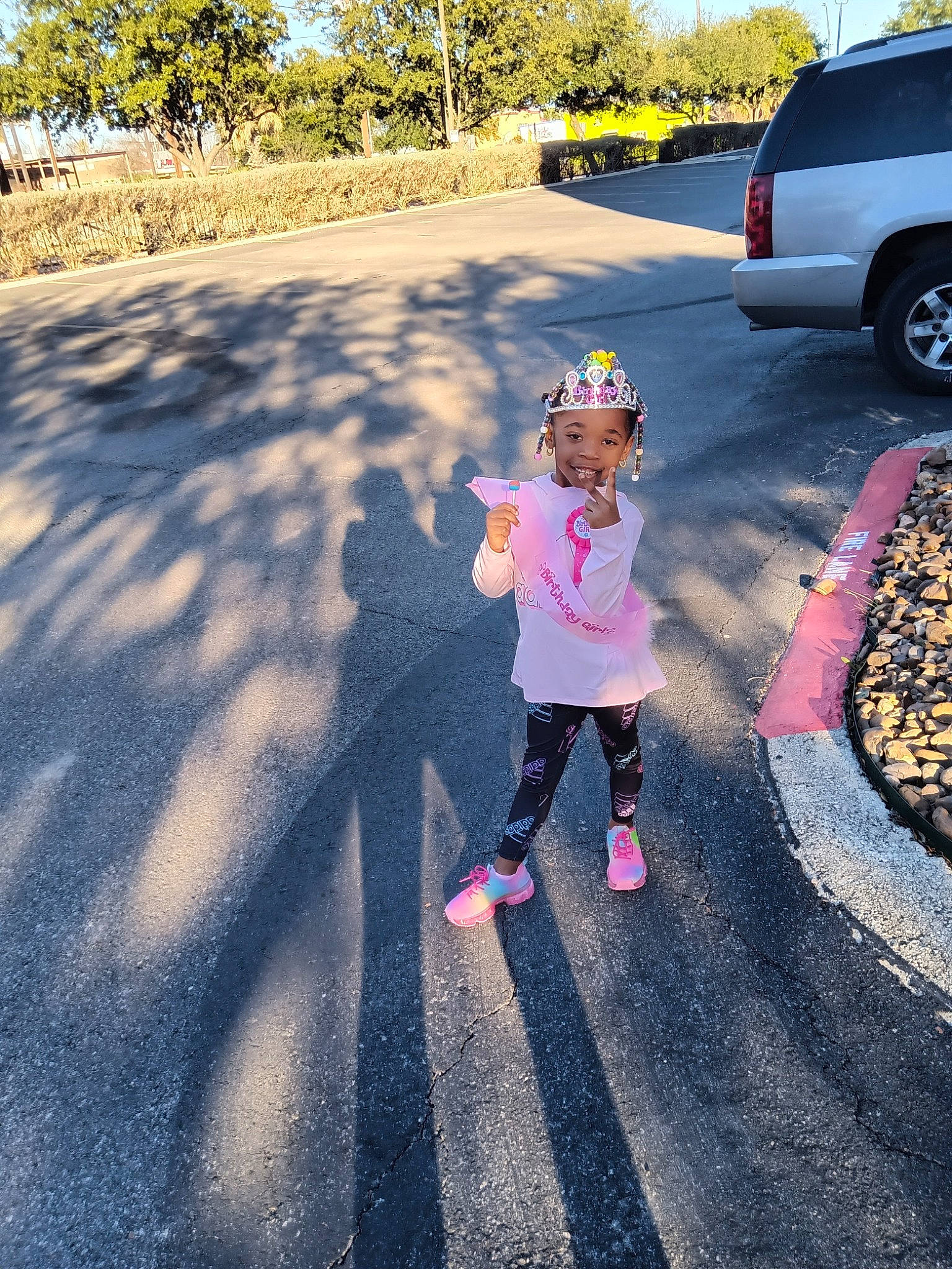 Shamar is registered to the contest to win money with this photo: asphalt, automotive_lighting, car, fun, grass, happy, hat, headwear, joy, leisure, person, plant, recreation, road, road_surface, sidewalk, sunlight, tints_and_shades, tire, toddler