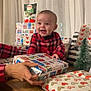 Isaac a rejoint le concours — aidez-le/la à gagner de superbes lots ! baby, celebration, child, christmas_tree, curtains, cute, face, festive, gift, hand, holiday, indoors, joyful, person, plaid, present, red_clothing, smiling, table, wrapping_paper