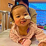 Anna joined the competition — help win amazing prizes! baby, child, hospital, medical_patch, pink_clothing, bed, adult, tongue_out, playful, smile, person, indoors, window, clock, furniture, healthcare, caregiver, headband, cute, hospital_room
