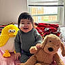 baby, child, smiling, plush_toy, stuffed_animal, yellow_bird, brown_dog, window, blanket, mickey_mouse, bed, indoors, happy, face, bandage, nasal_tube, cute, person, cozy, soft_toys