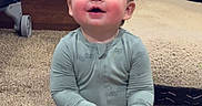 Kolter joined the competition — help win amazing prizes! baby, child, onesie, toy, carpet, fireplace, indoor, smiling, sitting, warm, cozy, furniture, floor, happy, young_child, person, playful, electric_fireplace, home, infant
