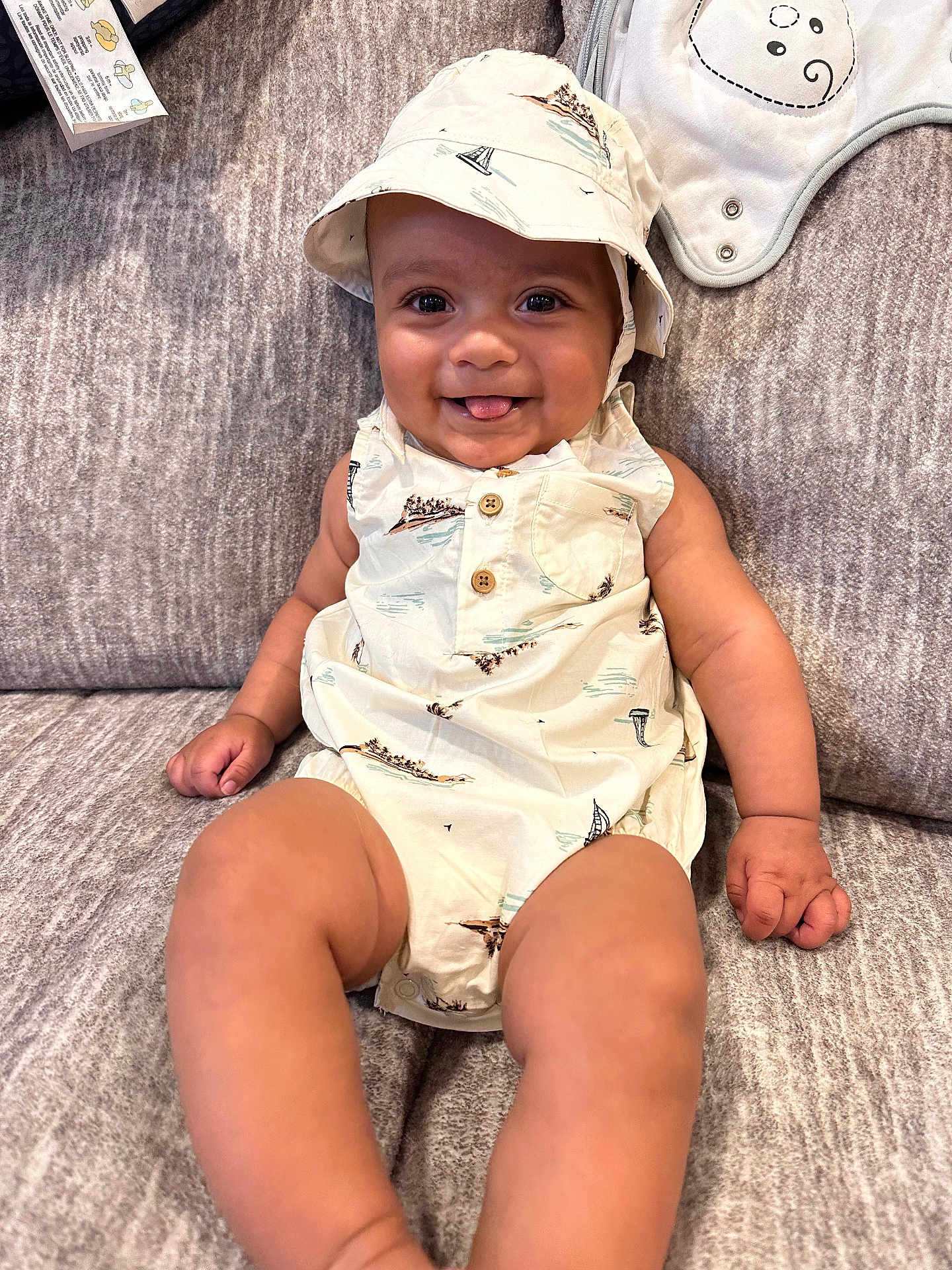 Atlas is registered to the contest to win money with this photo: baby, babylaughing, baseballcap, cap, clothing, couch, diaper, dress, face, furniture, happy, hat, head, person, photography, portrait, sitting, sleeve, smile, sunhat