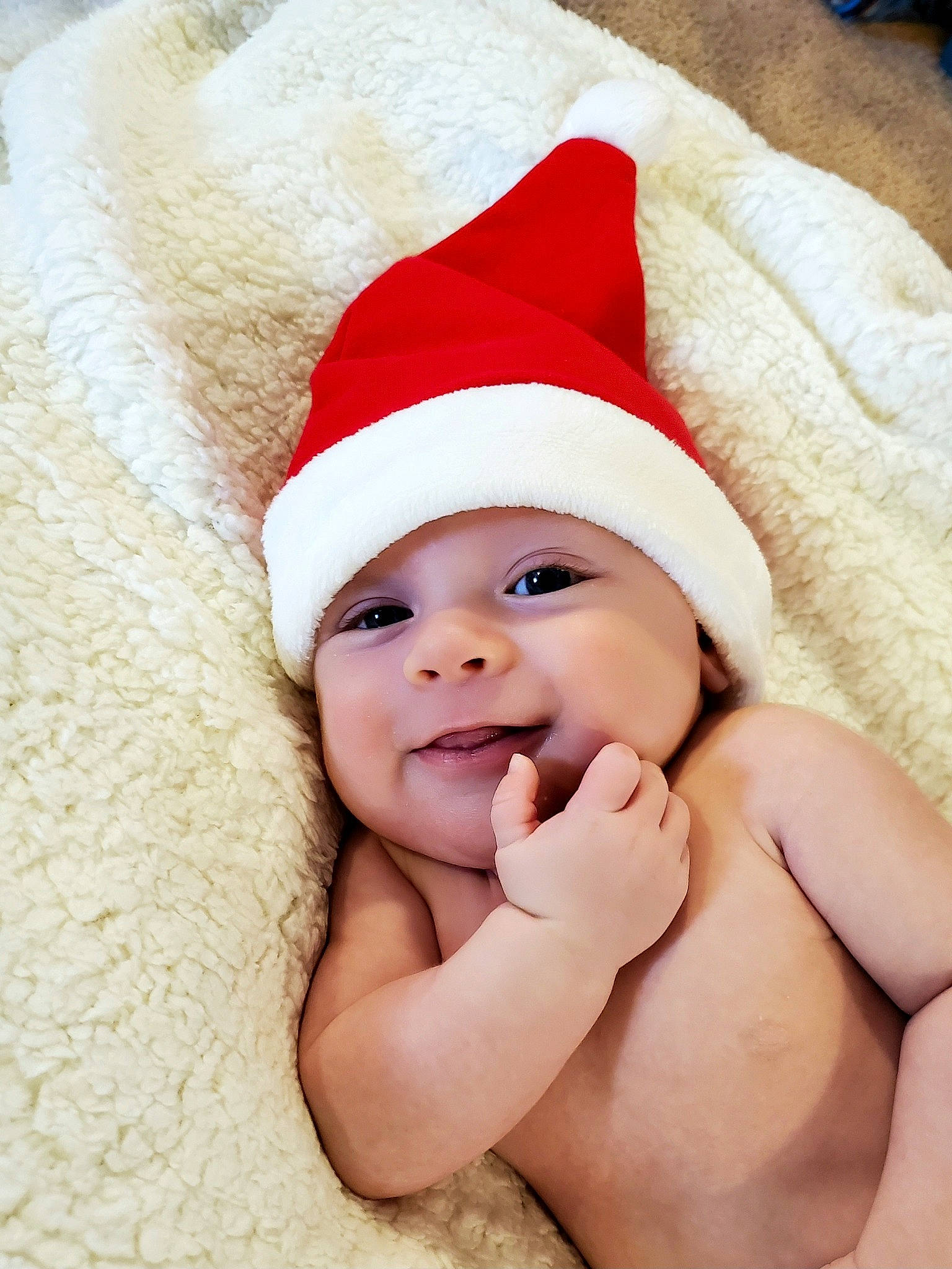 Gideon is registered to the contest to win money with this photo: baby, cap, carmine, child, comfort, costume_hat, event, fictional_character, fun, fur, gesture, happy, hat, headgear, headwear, holiday, linens, person, santa_claus, skin