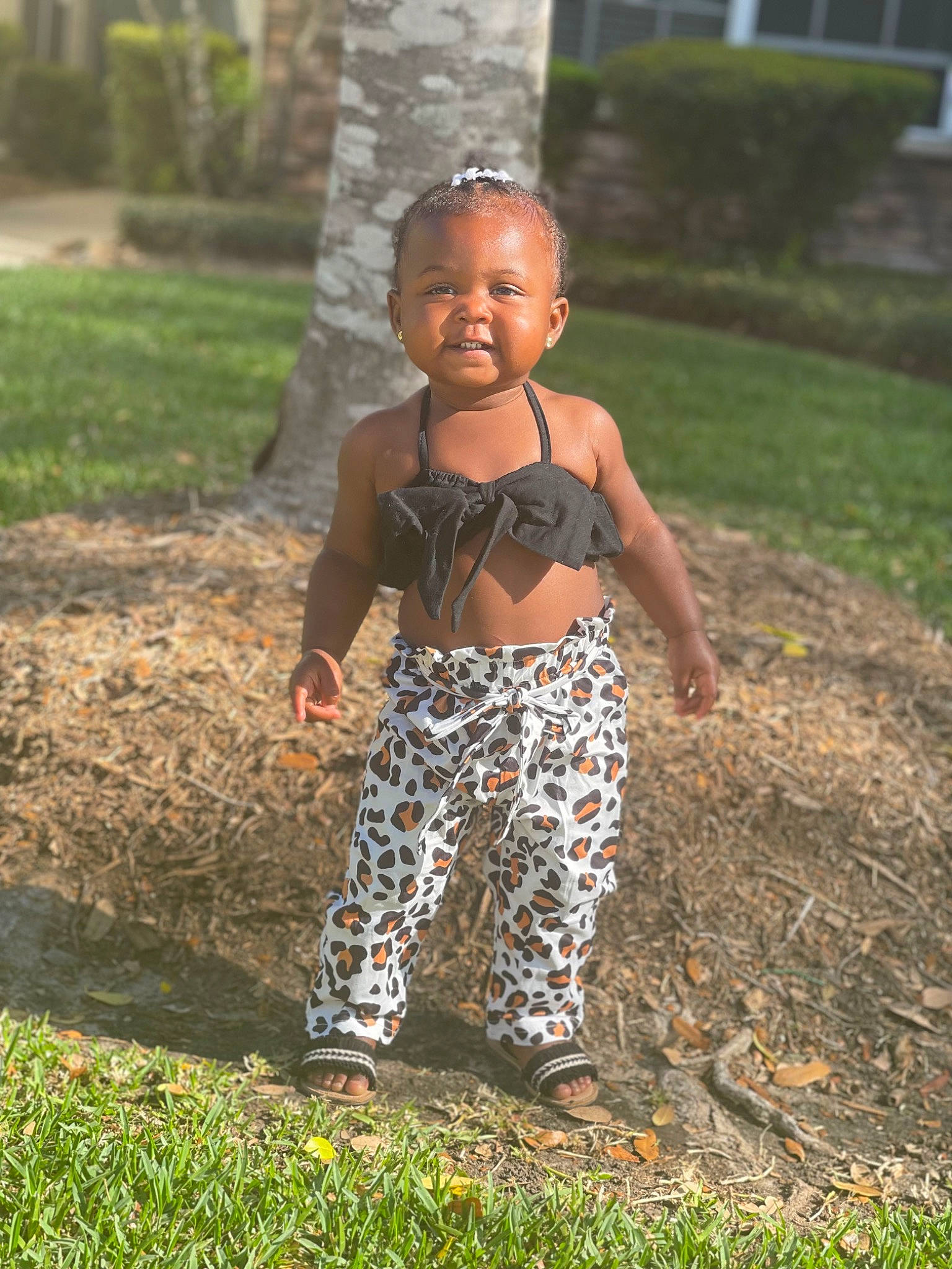 Brynlei is registered to the contest to win money with this photo: adaptation, eye, fawn, grass, happy, head, house, human_leg, leaf, leg, pattern, people_in_nature, person, plant, smile, soil, toddler, tree, tribe, trunk