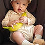 baby, child, car_seat, banana, hat, socks, teddy_bear, cute, infant, clothing, seatbelt, person, holding, fruit, indoors, expression, smiling, headwear, footwear, comfort