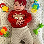 baby, blanket, cheerful, child, closeup, colorful, cute, face, hands, happy, headband, indoors, infant, lying_down, playtime, red_clothing, smiling, soft_pants, star_pattern, toy