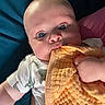 Ryker is registered to the contest to win money with this photo: baby, infant, blanket, orange_blanket, blue_background, dinosaur_print, clothing, hand, face, wide_eyes, curious, lying_down, skin, cute, toddler, child, indoors, soft_texture, mouth, expression