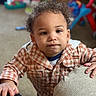 toddler, child, curly_hair, checkered_shirt, couch, hand, indoor, carpet, toys, blurred_background, person, young_child, face, portrait, casual_clothing, playing, home, expression, curious, baby