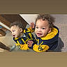 Kimoni is registered to the contest to win money with this photo: toddler, child, mirror, reflection, hoodie, yellow, navy, curly_hair, indoor, carpet, smiling, hands, face, person, clothing, curiosity, joy, expression, self_discovery, home