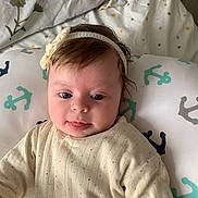 Dania participe au concours pour gagner de l'argent avec cette photo : baby, infant, headband, pillow, anchor_pattern, bed, blanket, clothing, cute, face, child, indoors, soft_lighting, portrait, sleepwear, smiling, young, person, resting, expression