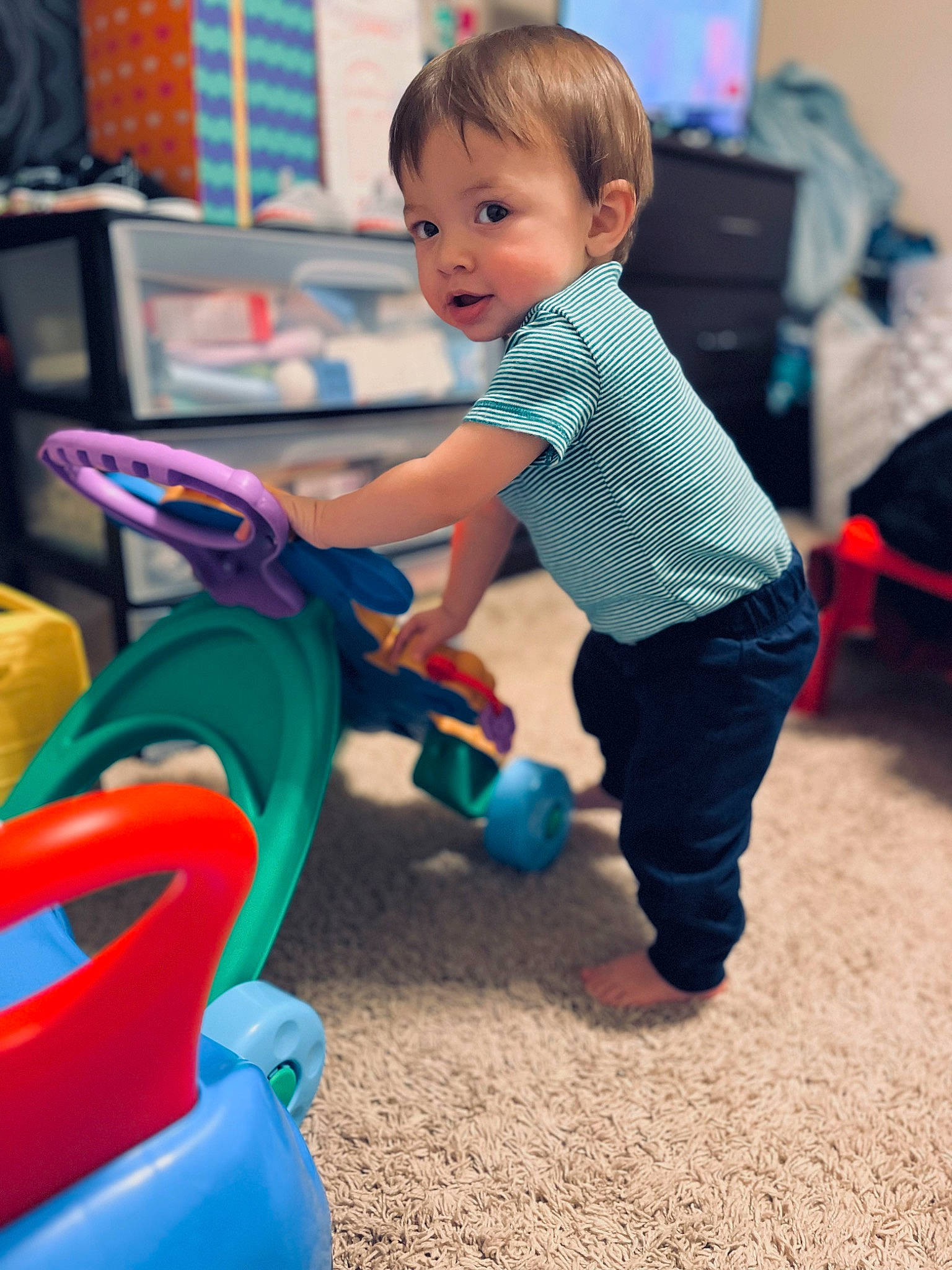 Jace is registered to the contest to win money with this photo: baby, baby_playing_with_toys, baby_toddler_clothing, child, city, electric_blue, event, fun, grass, happy, leisure, outdoor_play_equipment, person, play, playground, public_space, recreation, riding_toy, sitting, standing