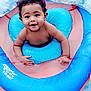 baby, blue, child, curly_hair, cute, float, fun, happy, infant, inflatable, outdoor, person, playful, pool, recreation, skin, smiling, summer, swimming, water