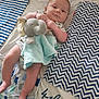 baby, blanket, blue, celebration, child, comfort, cute, diaper, elephant_toy, fabric, holiday, indoors, infant, lying_down, resting, smiling, soft_toy, striped_pattern, white, zigzag_pattern