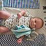 baby, baby_boy, baby_clothing, blanket, blue, child, cute, fabric, grey, home, infant, lying_down, onesie, pattern, sleeping_area, smiling, soft_toy, stuffed_toy, toddler, white