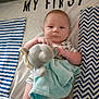 baby, bed, blanket, blue, chevron_pattern, child, clothing, comfort, cute, elephant_toy, expression, indoor, infant, lying_down, portrait, small_person, soft_toy, striped_pattern, toy, white
