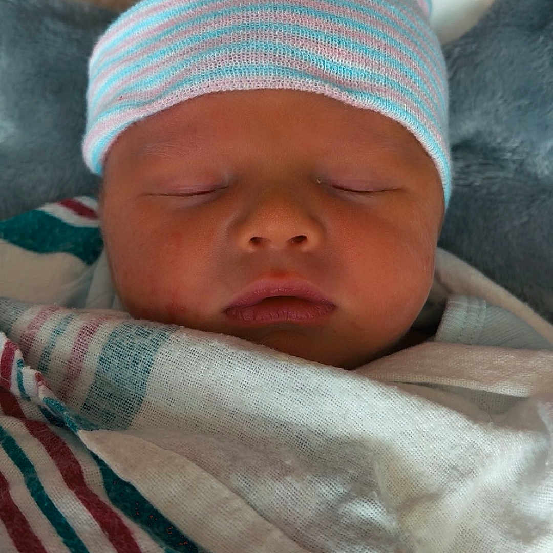 Van is registered to the contest to win money with this photo: baby, baby_clothes, blanket, child, closeup, cute, face, hat, indoors, infant, newborn, newborn_baby, peaceful, portrait, rest, sleep, sleeping, soft, striped_hat, swaddle