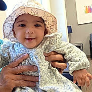 Nisa Siddique is registered to the contest to win money with this photo: adult, baby, child, clothing, cute, dress, face, furniture, hands, happy, hat, indoor, light, pattern, person, portrait, sitting, skin, smiling, window