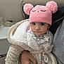 baby, blanket, child, cozy, cute, expression, face, fluffy_jacket, hand, holding, indoor, infant, knit_hat, person, pink_hat, pom_poms, portrait, soft_texture, warm_clothing, wide_eyes